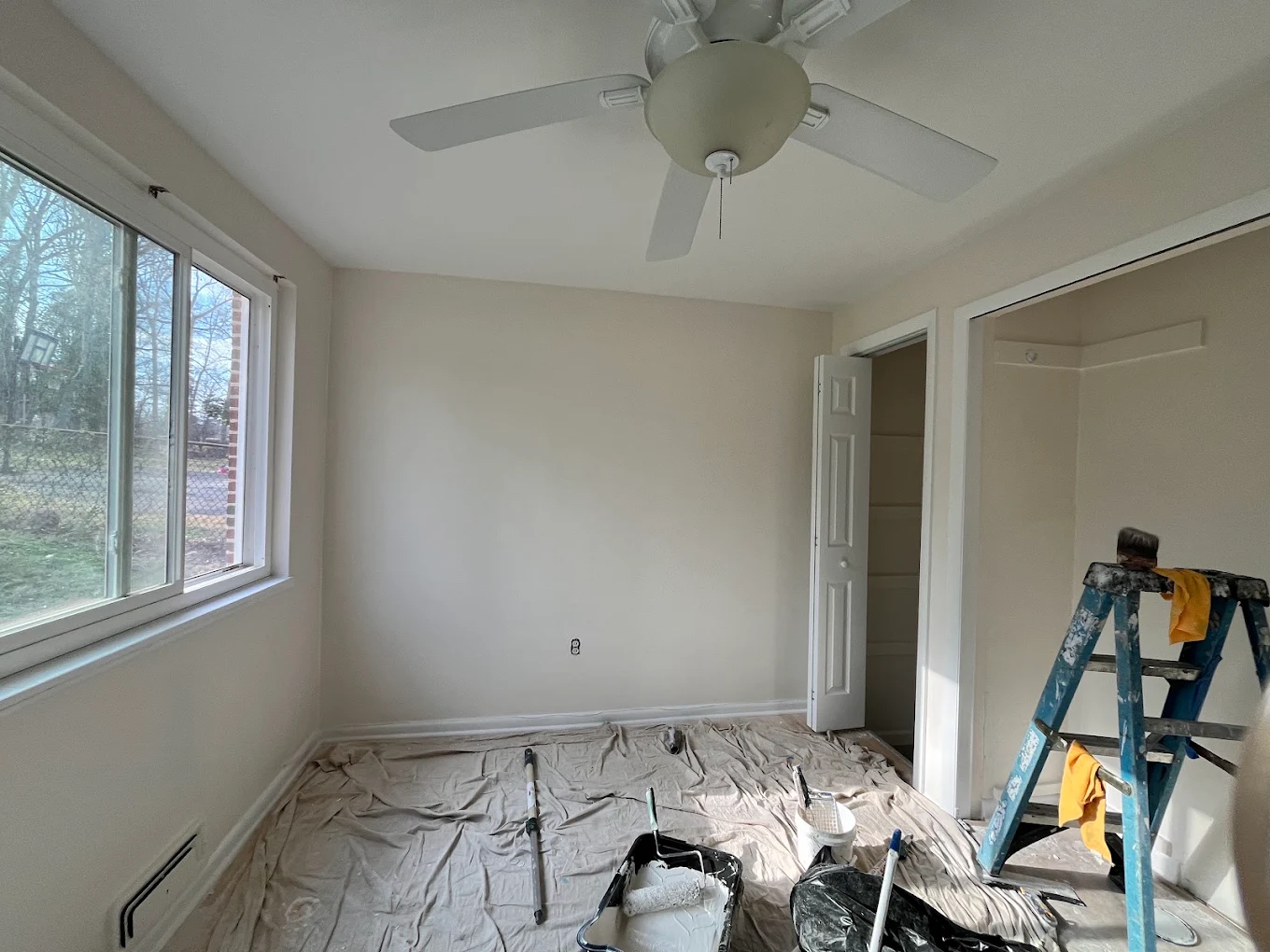 Bedroom mid-project with floors covered by drop cloths and freshly cut-in walls